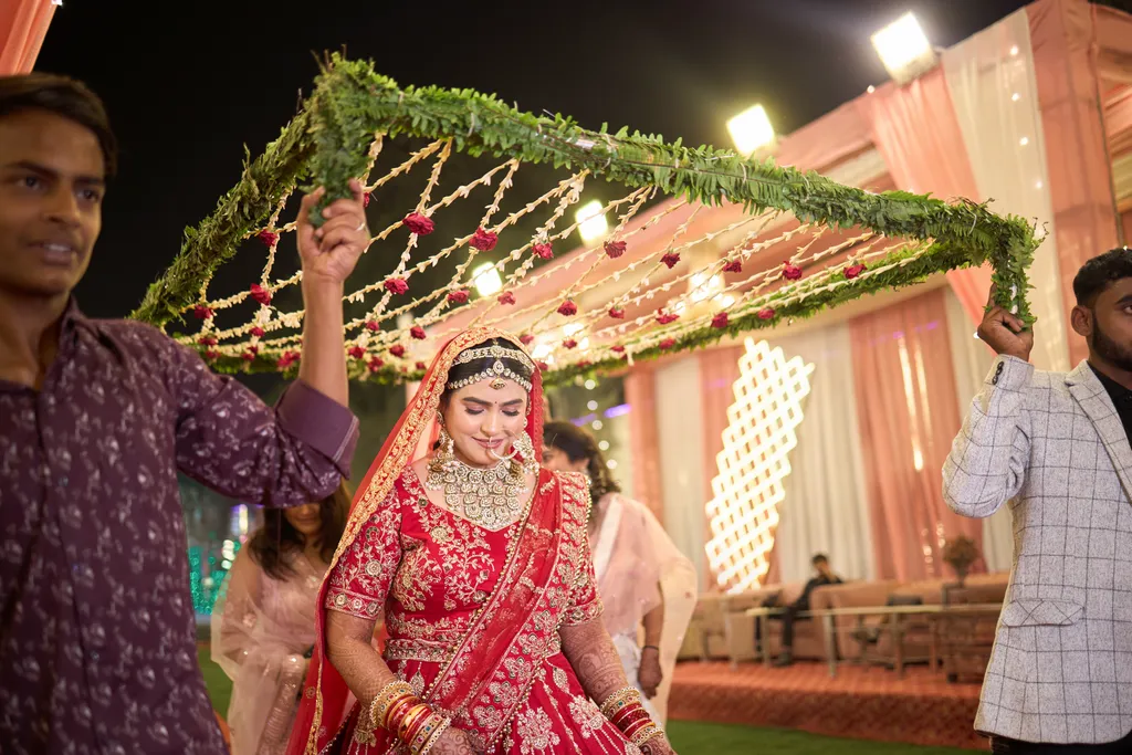 Bride walking towards the wedding stage under a floral chadar at R R Palace Marriage Lawn Varanasi by The WeddingShoot